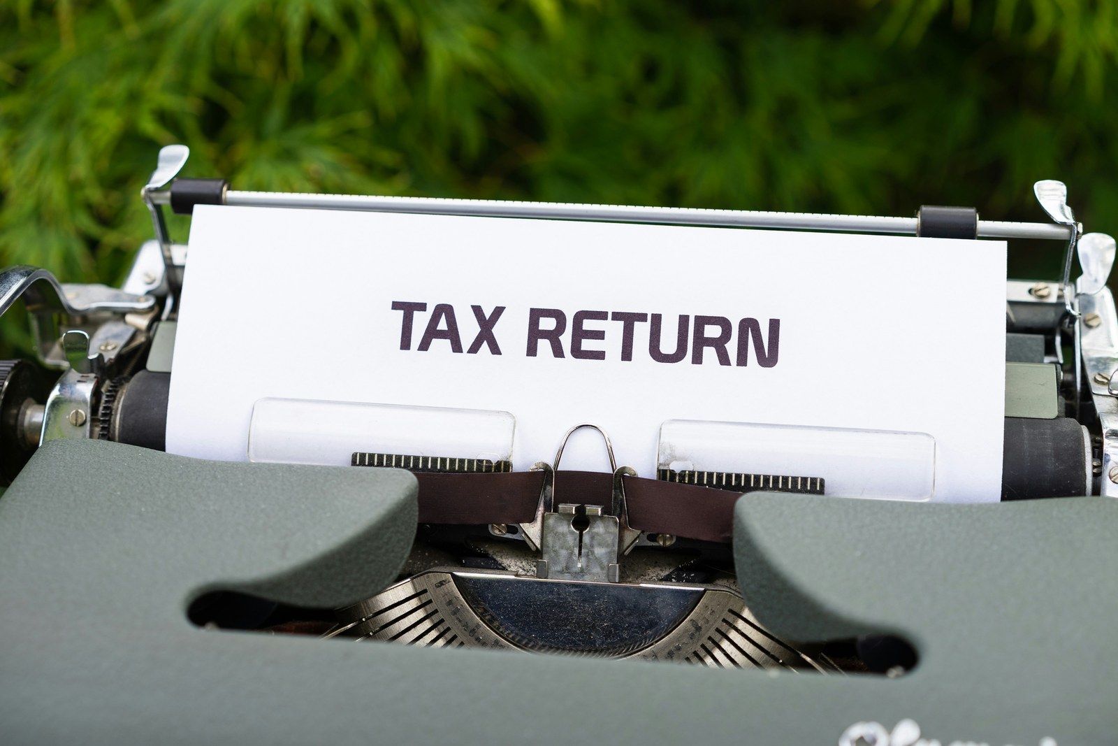 A typewriter with a page reading Tax Return rolled into it
